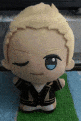 a stuffed doll with blonde hair is sitting on a green rug