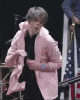 a man in a pink jacket is dancing on stage