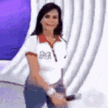 a woman is standing in front of a purple curtain and smiling .