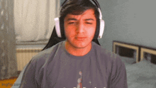 a man wearing headphones is sitting in a chair in a bedroom .