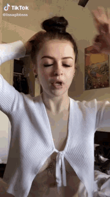 a woman with a tattoo on her stomach is wearing a very revealing white shirt .