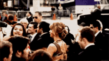 a woman in a gold dress is standing in a crowd