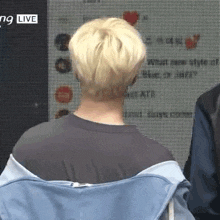 a man with blonde hair is sitting in front of a screen with the word live on it