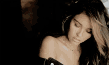a woman with long hair is standing in a dark room and looking at the camera .