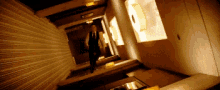 a man in a suit and tie is walking down a hallway with a light on the wall