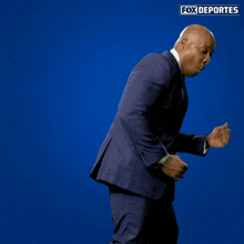a man in a suit and tie is dancing in front of a blue background with fox deportes written on it