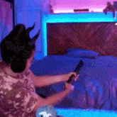 a woman with horns on her head is sitting on a bed holding a remote control .