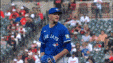 a baseball player wearing a blue jays jersey stands in front of a crowd