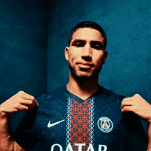 a man is wearing a blue shirt with the word qatar on it