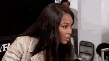 a woman with long black hair is wearing a white jacket and looking at something .