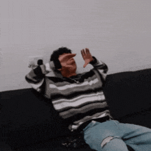 a man in a striped sweater is sitting on a black couch