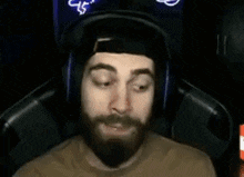 a man with a beard and headphones is sitting in a chair .