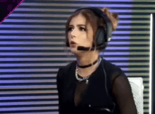a woman wearing headphones and a choker is sitting in front of a computer screen .