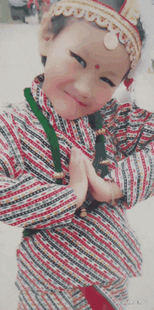 a little girl wearing a striped shirt and a headband with a coin on her forehead