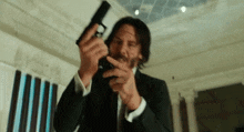a man in a suit and tie is holding a gun and pointing it at the camera .