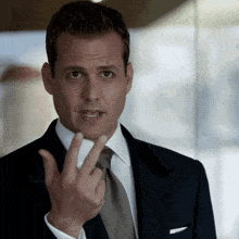 a man in a suit and tie holds up his finger