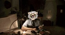 a man in a cat mask sits at a desk