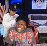 a man is sitting in a chair with a woman standing behind him and making a funny face .