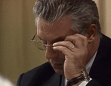 a man wearing glasses is covering his face with his hands