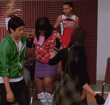 a girl in a whhs cheerleader uniform is standing next to a man in a green jacket