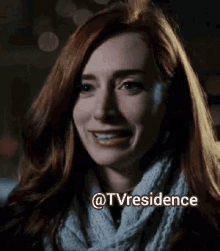 a woman with red hair wearing a white scarf and smiling with the words @tvresidence behind her