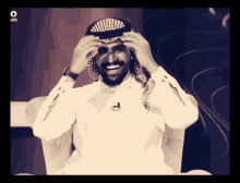 a man wearing a white shirt and a black head scarf is smiling