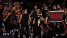 a group of wrestlers are standing in front of a crowd .