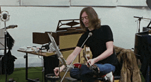 a man sits on a chair playing a guitar