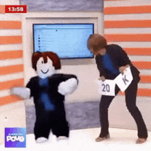 a woman is standing next to a roblox character dancing in front of a television .