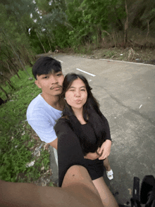 a man and a woman are posing for a picture on a road