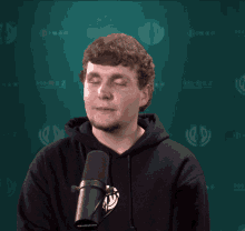 a man wearing a black hoodie stands in front of a microphone with the word hirez behind him