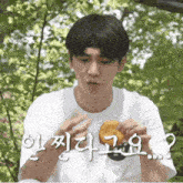 a young man in a white shirt is holding a piece of food in his hand .