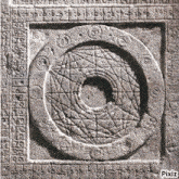 a stone carving of a circle with a hole in the middle surrounded by numbers