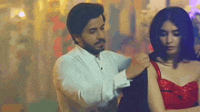 a man in a white shirt is helping a woman in a red dress .
