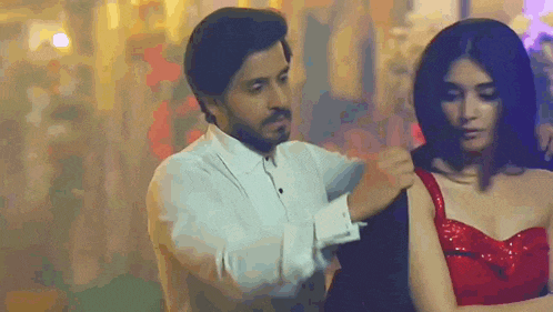 a man in a white shirt is helping a woman in a red dress .