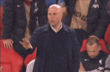 a bald man in a suit stands in a stadium with red seats and a sign that says burger king on it