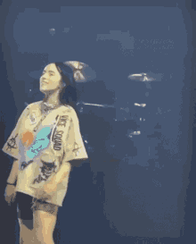billie eilish is dancing on a stage while wearing a sweater and shorts .