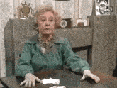 a woman is sitting at a table with her hands on the table .