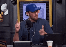 a man wearing a blue hat and ear buds talking into a microphone