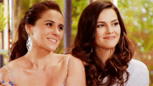 two women are sitting next to each other and smiling .