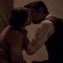 a man and a woman are kissing in front of a wall