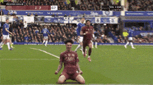 a soccer player is kneeling down on the field with a sign that says premier league behind him
