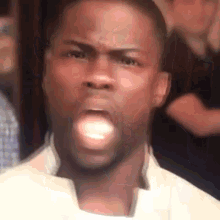 a man in a white jacket is making a funny face with his mouth open .