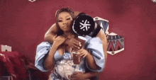 a man is carrying a woman on his shoulders while she holds a hat on her head .