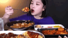 a woman is eating a bowl of food with a spoon in her mouth