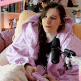 a woman in a purple hoodie is sitting in a chair with a microphone in front of her .