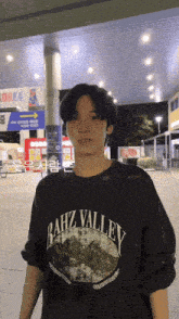 a man wearing a bahz valley shirt stands in front of a korea sign