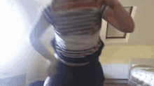 a man in a striped shirt is standing in a room with a window .
