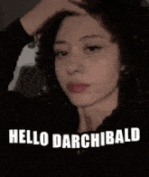 a woman with curly hair is standing in front of a sign that says " hello darchibald "