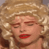 a woman wearing a blonde wig and red lipstick .